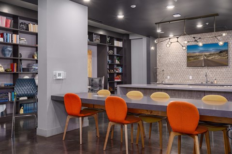 A modern dining room with a grey table and orange chairs.