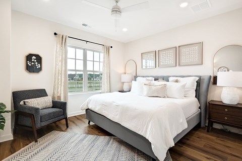 A bedroom with a large bed, a chair, and a window.