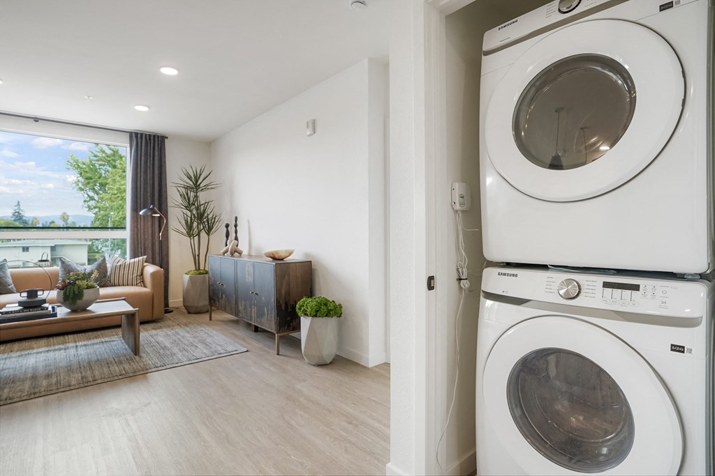 a washer and dryer in a living room with a couch and a window