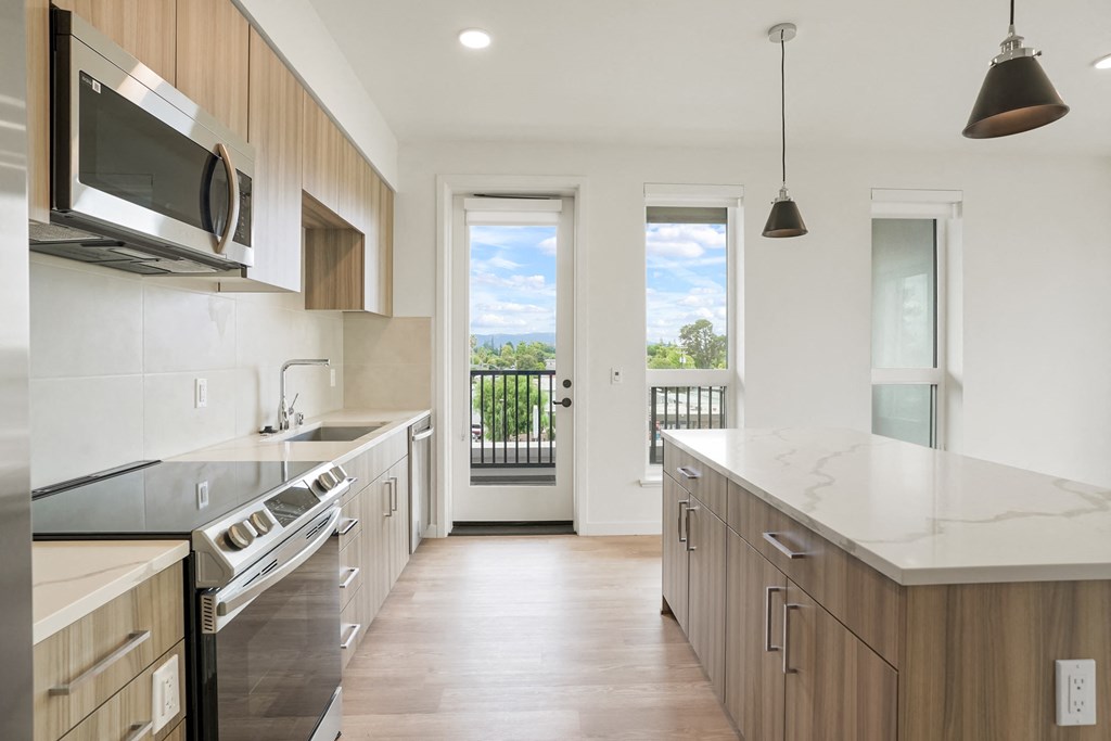 a large kitchen with wooden cabinets and a door to a balcony