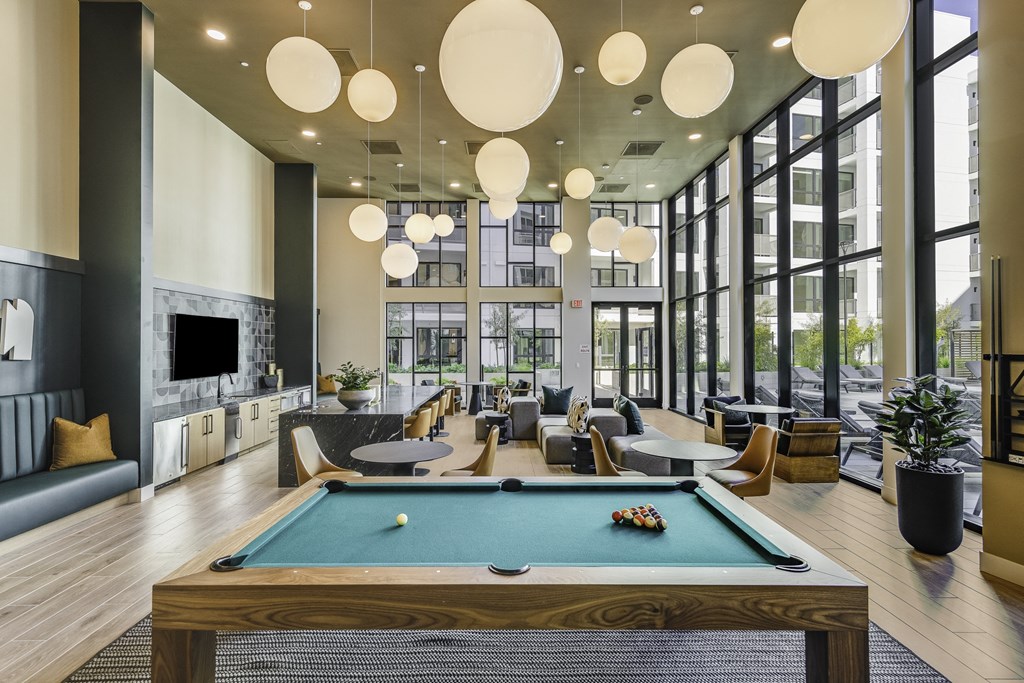 A billiard table is in the middle of a room with a lot of windows.