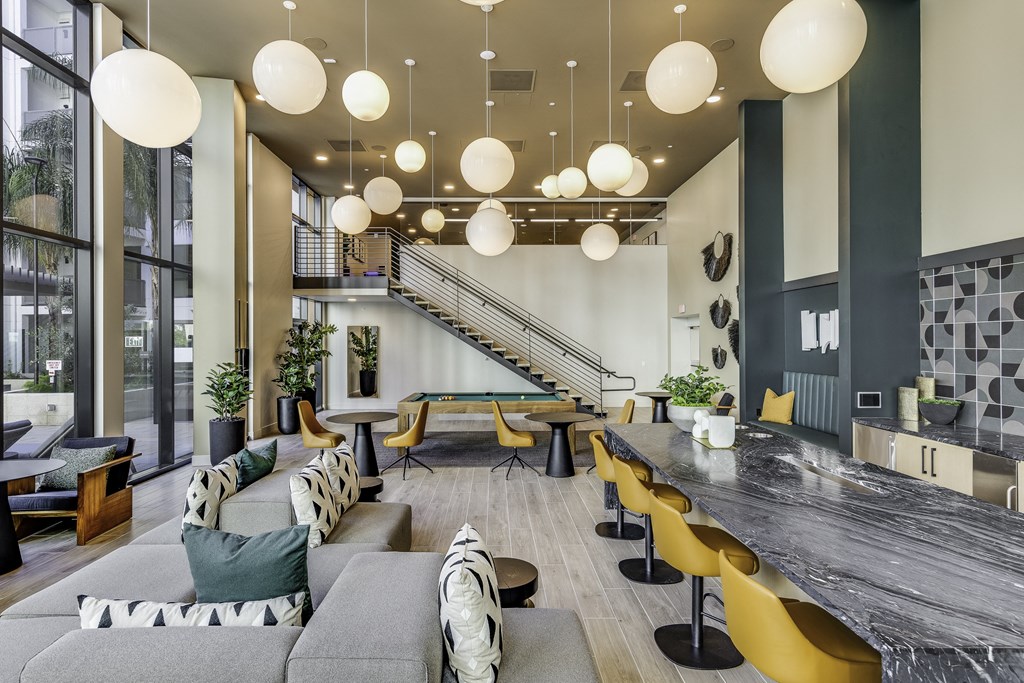 A modern living room with a staircase and a long table.