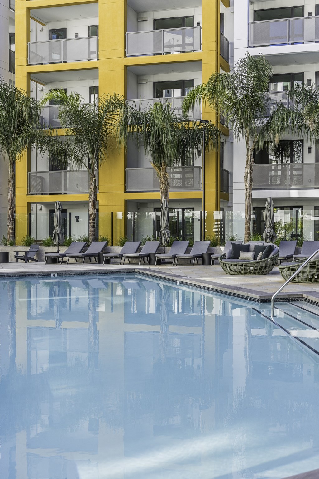 A yellow building with a pool in front.