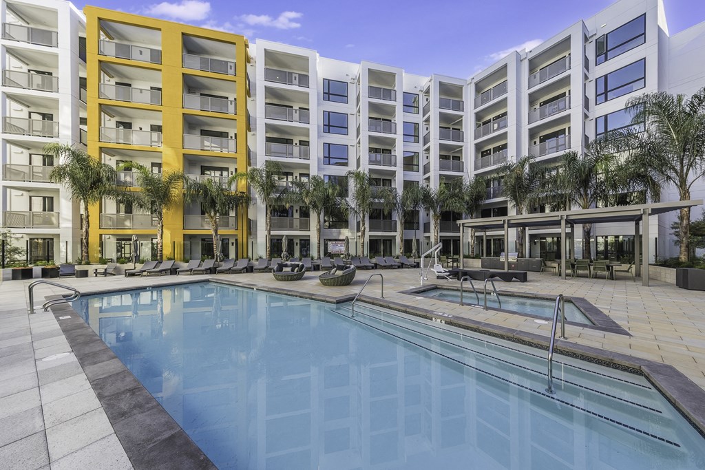 A large swimming pool is surrounded by apartment buildings.