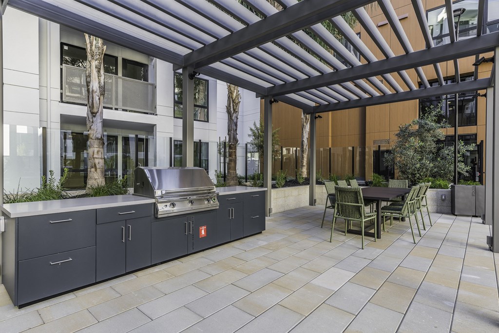 A patio with a table and chairs and a grill.
