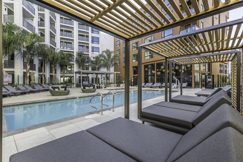 A pool area with sun loungers and a wooden pergola.