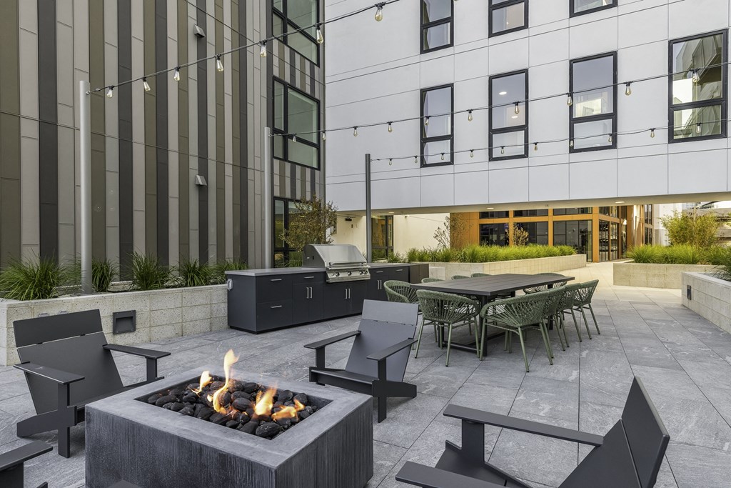 A modern outdoor seating area with a fire pit and chairs.
