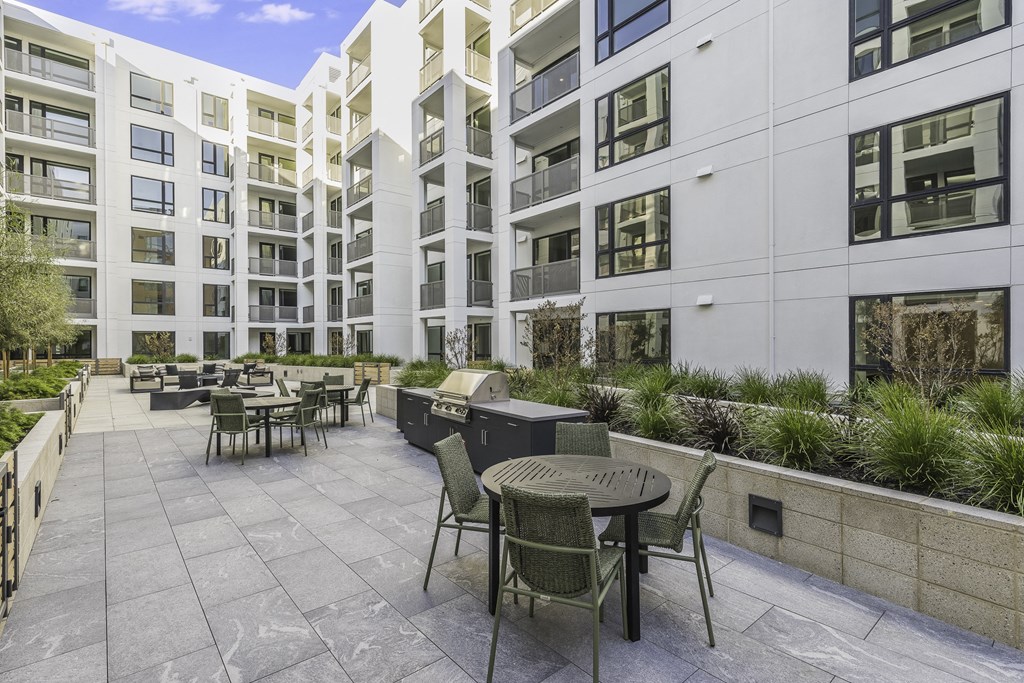A patio with a table and chairs is surrounded by a wall and a building.