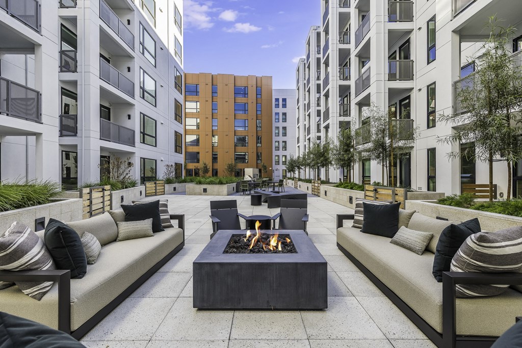 A modern outdoor seating area with a fire pit in the center.