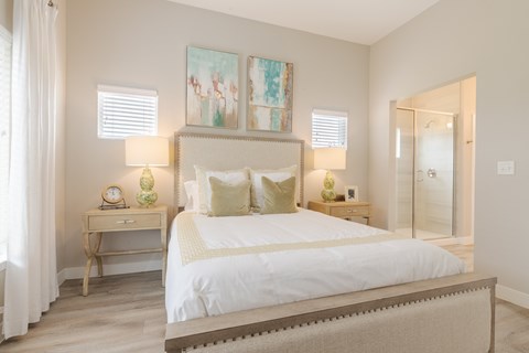 A bedroom with a large bed, two nightstands, and a painting on the wall.