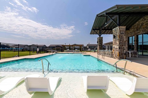 A pool with white chairs and a building in the background.