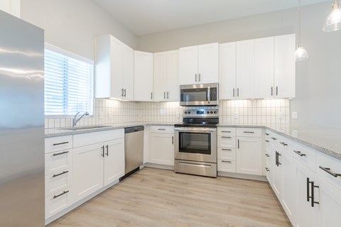 A kitchen with white cabinets and a stainless steel refrigerator.