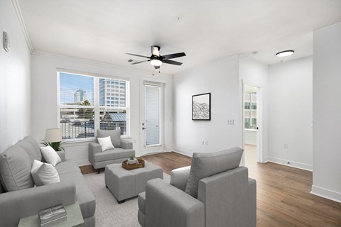 A living room with grey couches and a ceiling fan.