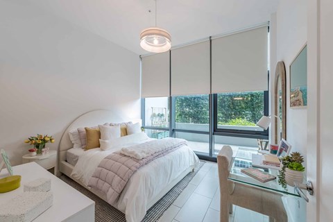 A bedroom with a large bed and a glass table with a plant on it.