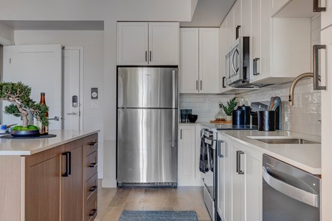 A modern kitchen with a stainless steel refrigerator and wooden cabinets.