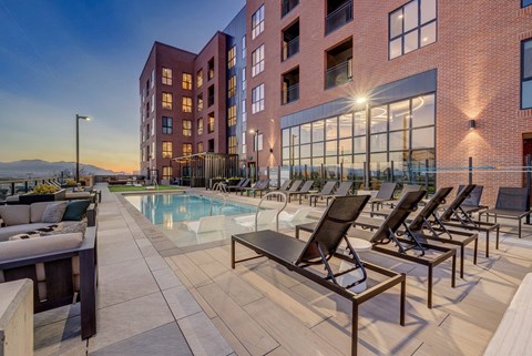 A pool area with lounge chairs and a building in the background.