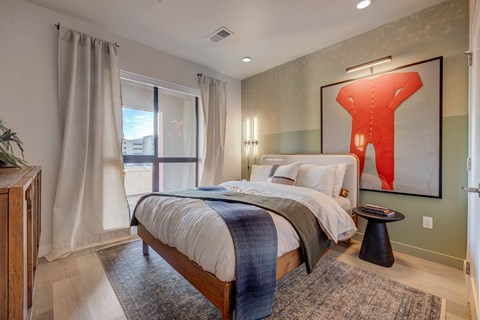 A bedroom with a large bed and a red abstract painting on the wall.