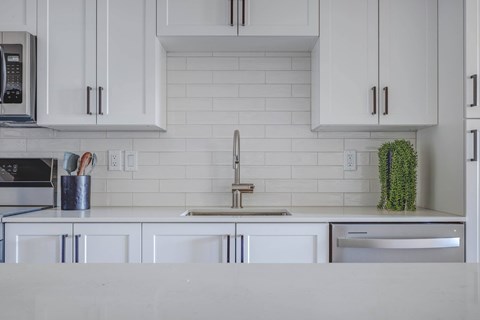 A kitchen with white cabinets and a white countertop.