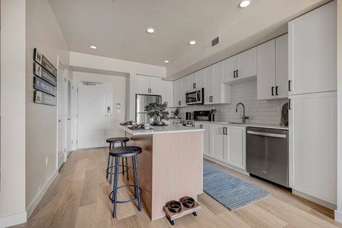 A kitchen with white cabinets and a wooden island.