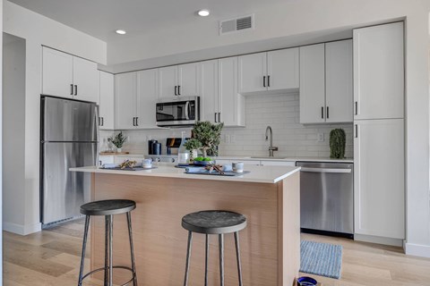 A kitchen with white cabinets and a wooden island.