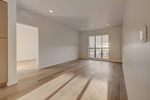 A room with wooden floors and a window with blinds.
