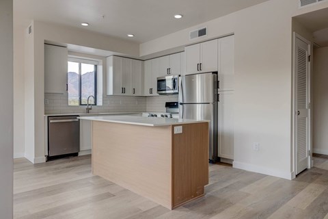A kitchen with a wooden island and stainless steel appliances.