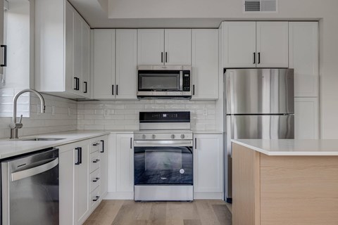 A modern kitchen with stainless steel appliances and white cabinets.