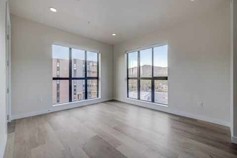 A spacious room with large windows and wooden flooring.