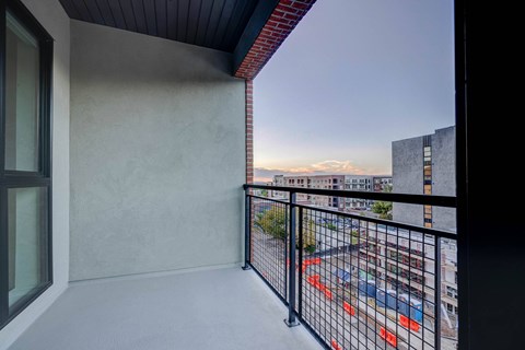 A balcony with a black railing and a view of a parking lot.