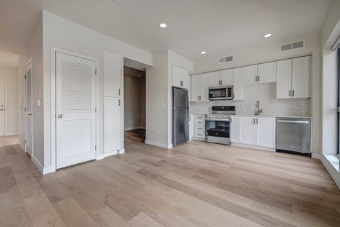 A kitchen with white cabinets and wooden floors.