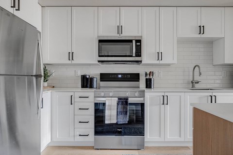 A modern kitchen with a stainless steel refrigerator, microwave, oven, and sink.