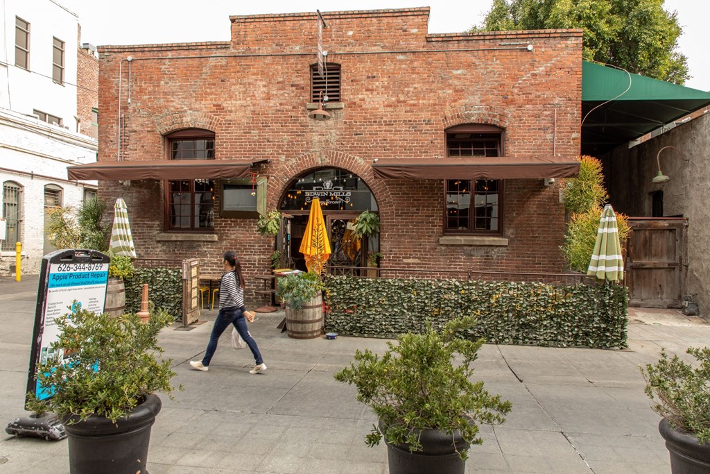 a woman walks past a brick building with a green awning