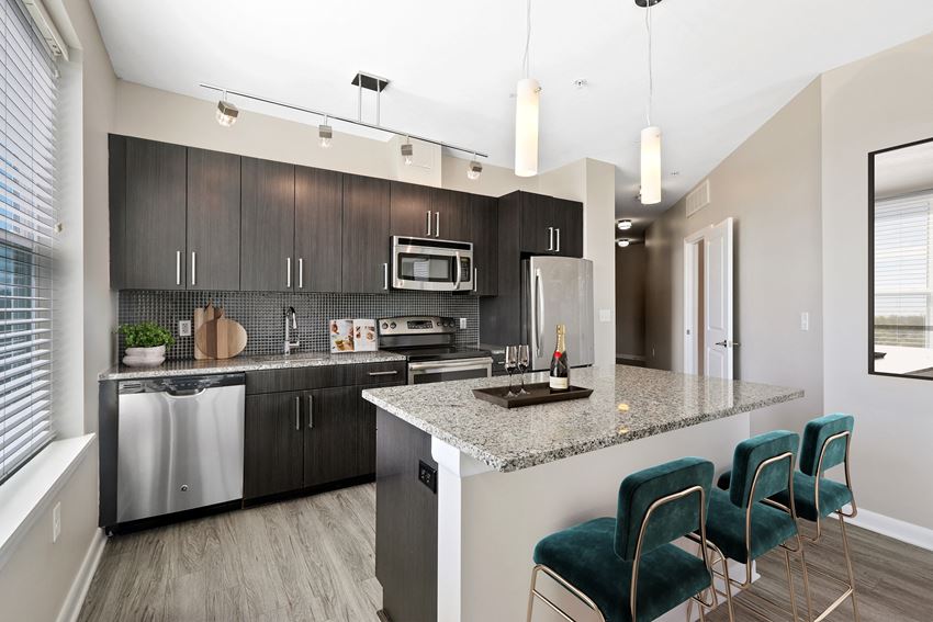 a kitchen with dark cabinets and a large island with a granite countertop