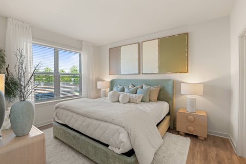 A bedroom with a large bed and a window with blinds.