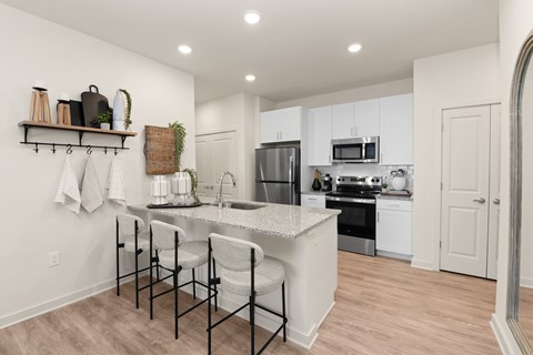 A kitchen with white cabinets and a black and white bar stool.