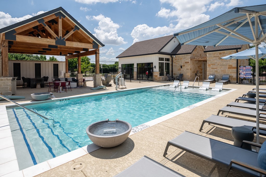 a swimming pool with lounge chairs and a building with a pavilion