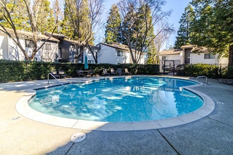A round above ground pool with a white border and a concrete patio.
