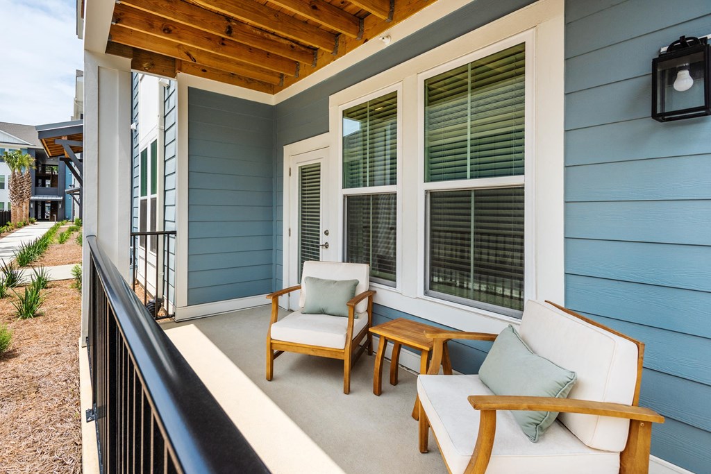 a covered porch with two chairs and a table