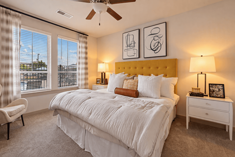 A bedroom with a large bed, a chair, and a ceiling fan.