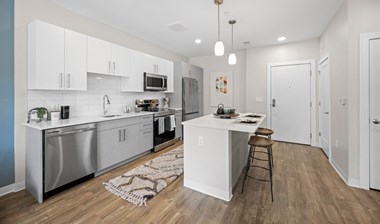 Model kitchen with stainless steel appliances, and kitchen island with seating