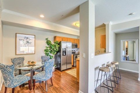 a dining room with a table and chairs and a kitchen with a refrigerator