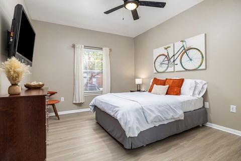 A bedroom with a large bed and a television on the wall.