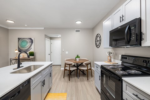 A modern kitchen with a table and chairs in the middle.