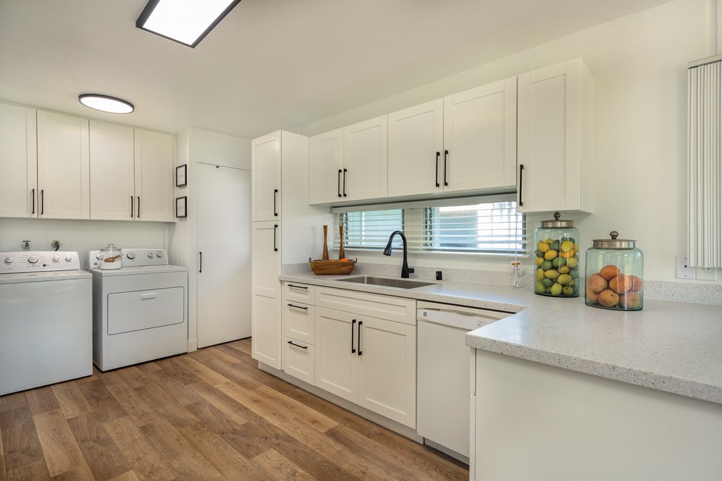 a kitchen with white cabinets and white appliances and a counter top