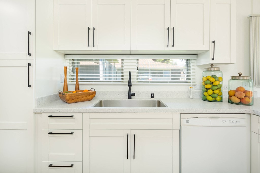 a white kitchen with white cabinets and a sink