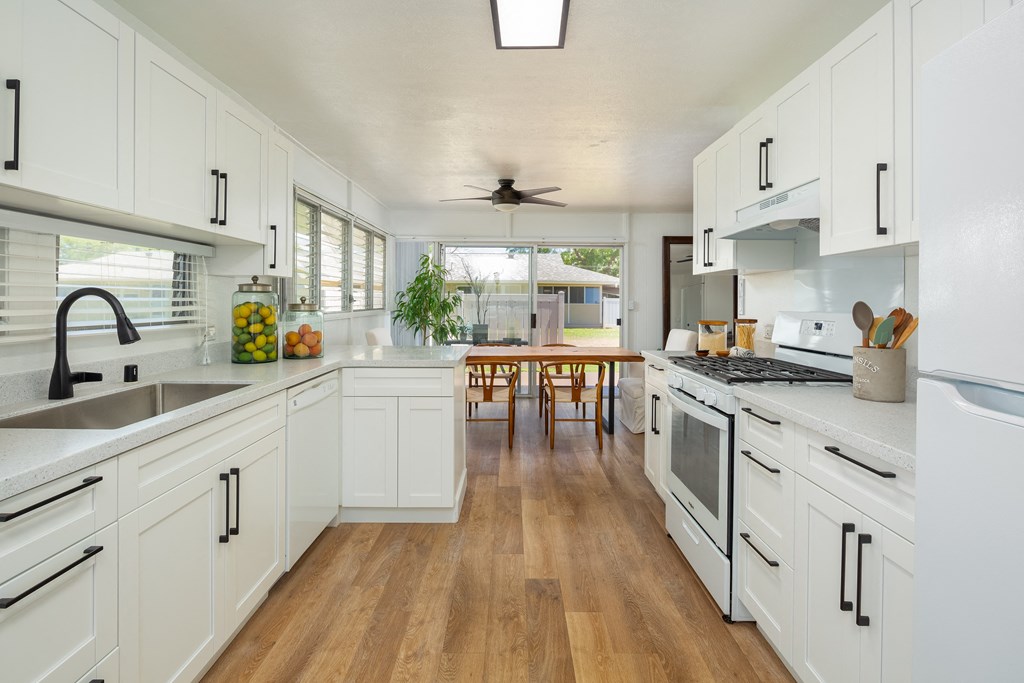 a large kitchen with white cabinets and a wooden floor