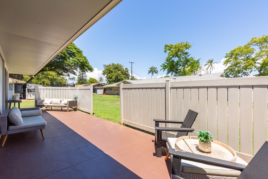 a patio with chairs and a table and a fence
