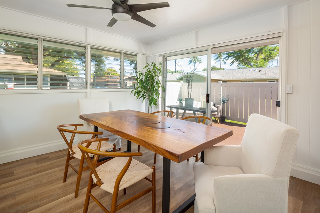 a dining area with a wooden table and chairs and a ceiling fan