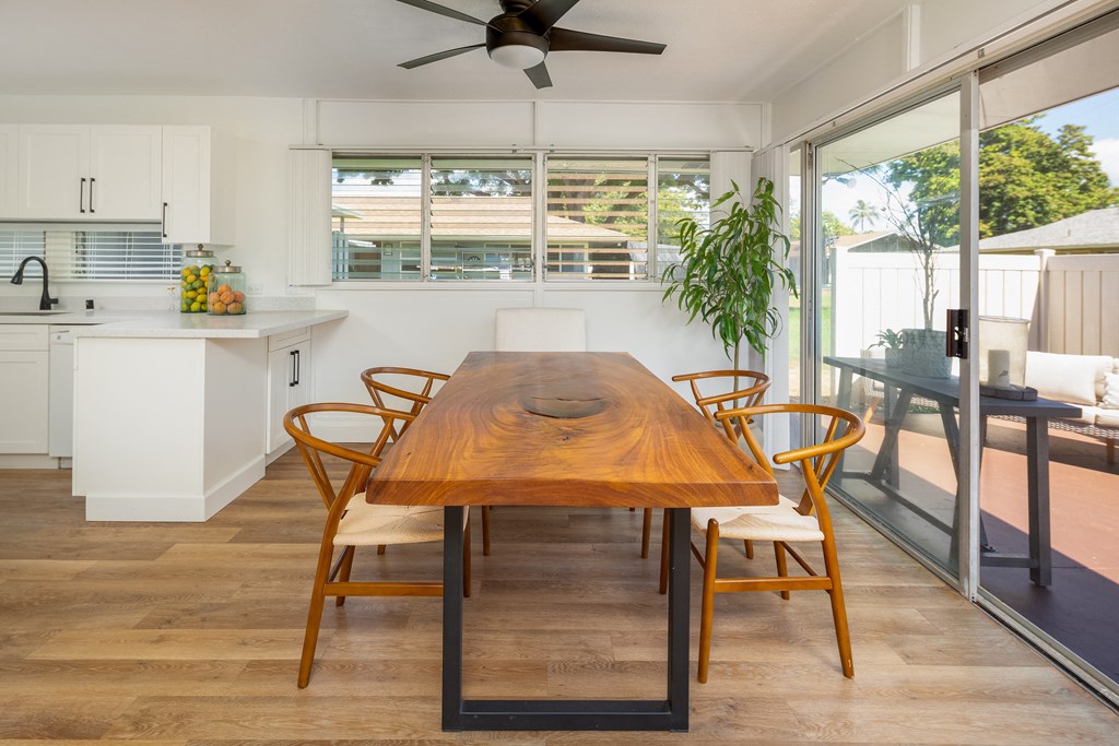 a dining area with a wooden table and chairs and a kitchen with sliding glass doors