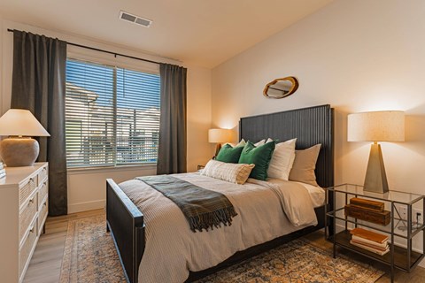 A bedroom with a large bed and a window with blinds.